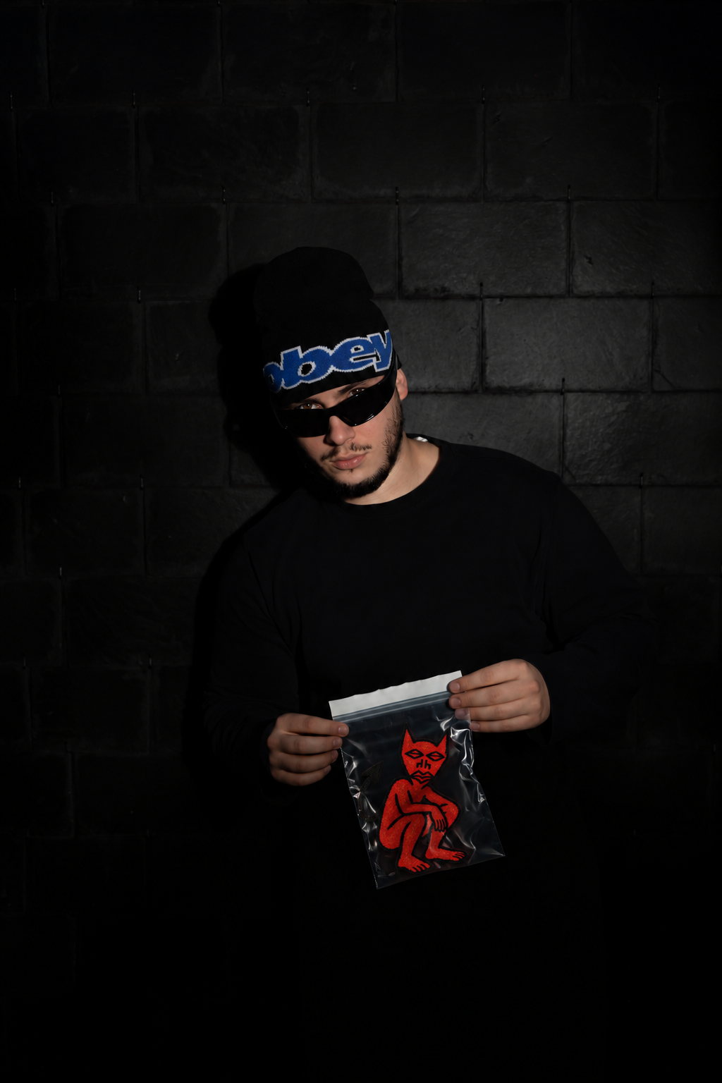 PETRYJKA tenant un sachet illustré du diable rouge de CONFESSION